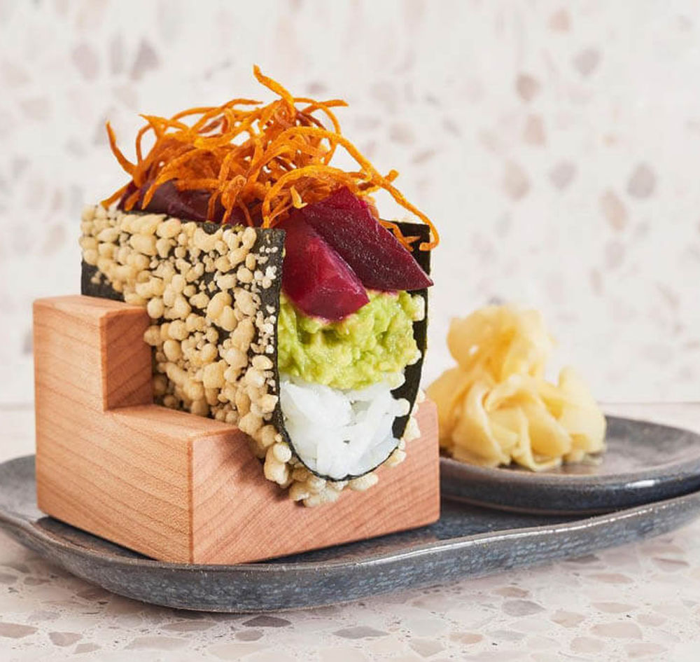 Hand rolls served upright in a solid wood hand roll holder at a restaurant table